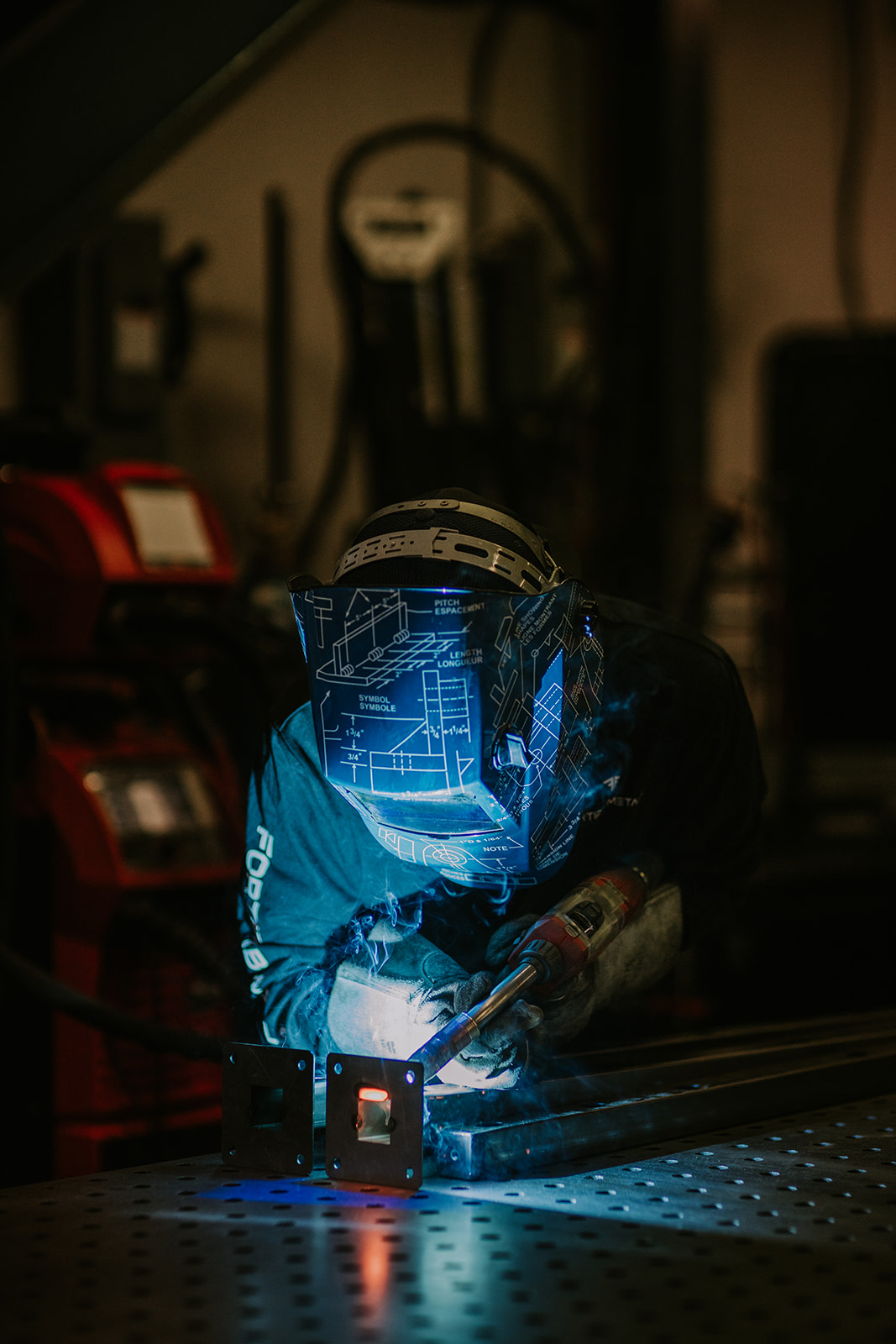 Welder producing a blue arc while joining metal components.